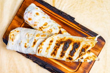 İki altın kahverengisi ızgarada pişmiş ve ahşap bir tahtada sunulmuş. Sıcak, cezbedici aroması tadını çıkarmaya hazır lezzetli bir yemek olduğunu gösteriyor..