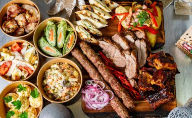 Izgara etler, taze salatalar ve ahşap bir tahtaya yerleştirilmiş lezzetli aperatiflerin yer aldığı özenle hazırlanmış bir ziyafet. Dostlar ve ailelerle şenlikli bir kutlama için mükemmel..