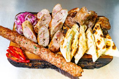 Şiş, sosis ve ekmeğin yanı sıra taze soğan ve biberin de dahil olduğu çeşitli ızgara etlerle dolu canlı bir gösteri, canlı bir toplantıda zengin bir mutfak geleneğini gözler önüne seriyor..