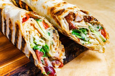 Izgara iki paket sergilenerek rengarenk tavuk, marul, domates ve diğer taze malzemelerin içeriği ortaya çıkıyor. Bu iştah açıcı yemek tatmin edici bir yemek için mükemmel..