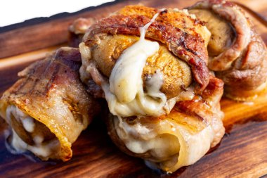 Pastırma vitrinine sarılmış etli börekler, yanlardan erimiş erimiş peynir. Yemek kırsal ahşap bir tabakta servis ediliyor. Et severler için mükemmel..