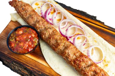 Yumuşak bir ekmeğin üzerine taze soğan dilimleriyle süslenmiş yumuşak bir kebap. Lezzetli bir sos eşliğinde, bu yemek sağlıklı bir yemek için mükemmel..