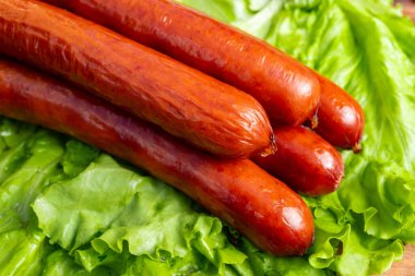 Sulu ızgara sosisler taze marullardan oluşan canlı yeşil bir yatakta otururlar. Bu kurgu yaz barbeküsü ya da piknik için mükemmel. Lezzetli bir açık hava ziyafeti davet ediyor..