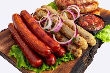 Ahşap bir tahtada, salata, soğan ve yanında salsa sosu olan ızgara sosis seçimi. Yaz barbeküsü için mükemmel ya da arkadaşlarla dışarıda toplanmak için..