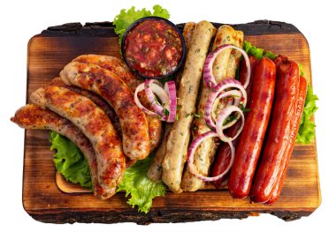 Tahta bir tabakta ızgara sosis ve yanında da soğan ve marulla süslenmiş salsa sosu. Yaz barbekü partisi için mükemmel..