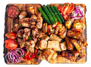 Canlı bir tabakta taze sebzelerin yanında ızgara et çeşitleri yer alıyor. Sulu tavuk kanatları, baharatlı domuz eti ve renkli domatesler yaz yemeği için mükemmel bir ziyafet hazırlar..