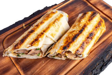 İki ızgara et ambalajı ahşap bir tahtaya güzelce yerleştiriliyor ve çıtır çıtır, altın sarısı dış görünüşlerini sergiliyorlar. Taze otlar renk katar, bu lezzetli yemeği servis etmeye hazır hale getirir..