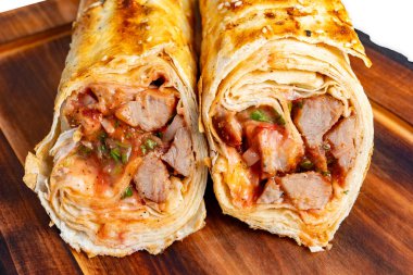 Taze rulo düz ekmekler lezzetli et ve erimiş peynirle cömertçe doldurulur, ahşap bir tahtanın üzerinde servis edilir. Hızlı bir yemek ya da atıştırmalık için mükemmel..