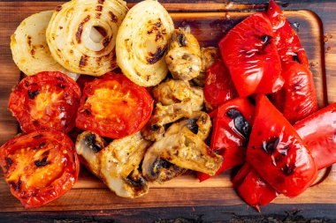 Izgara domates, soğan, mantar ve kırmızı biber rengarenk bir şekilde ahşap bir tahtaya dizilir ve akşam vakti arka bahçedeki barbekü partisinin sıcaklığını yakalar..