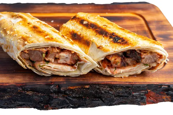 İki ızgarada ahşap bir tahtanın üzerinde, içi taze et ve taze malzemelerle dolu, altın-kahverengi, mükemmel kavrulmuş bir dış görünüş sergiliyor..