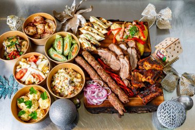 Canlı bir servis tabağında rengarenk mezelerin yanında çeşitli etler sergileniyor. Bayram kutlaması için mükemmel. Karışımda ızgara kebaplar, lezzetli tacolar ve taze salatalar var..