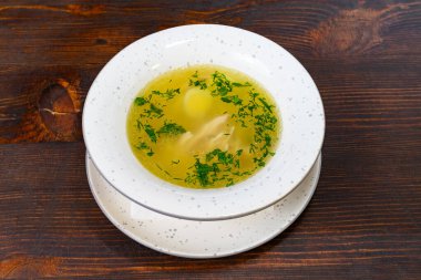 Taze bitkilerle süslenmiş lezzetli tavuk çorbası ve beyaz bir kasede yumurta. Bu rahatlatıcı yemek serin bir akşamda sıcak bir yemek için idealdir..