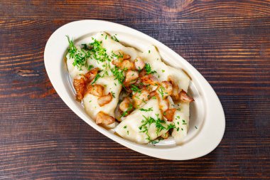 Gevrek pastırma parçaları ve taze otlarla doldurulmuş doyurucu hamur köfteleri. Tabak kırsal ahşap bir masada sunuluyor. Öğle veya akşam yemeği için harika bir yemek sunuluyor..