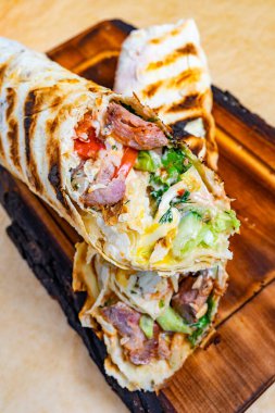 Izgara burrito, et katmanları, taze sebzeler ve soslar, yumuşak tortilla ile sarılmış. Bu lezzetli yemek hızlı bir öğle yemeği ya da atıştırmalık için mükemmel..