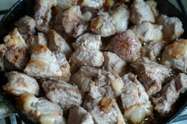 Domuz parçaları mükemmel bir şekilde kahverengi ve dökme demir tavada cızırdıyor. Et yumuşak ve sulu. Mutfakta lezzetli bir koku bırakıyor..