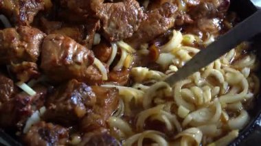 Cızırdayan sığır eti parçaları tavada dilimlenmiş soğanla pişirilir ve lezzetli aromalar bırakır. Yemek nazikçe kaynıyor, lezzetli bir yemeğin tadını arttıran zengin bir sos yaratıyor..