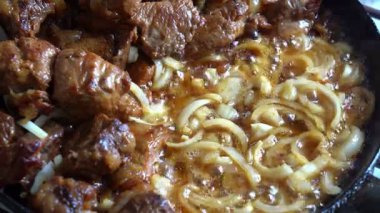 Et parçaları yavaş yavaş dilimlenmiş soğanla pişiriliyor ve zengin ve lezzetli bir güveç oluşturuyor. Rahatlatıcı koku mutfağı dolduruyor, sıcak bir yemek için mükemmel..