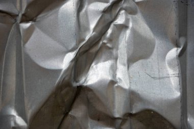 Yansıtıcı yüzey buruşmanın yarattığı karmaşık desenleri gösteriyor. Işık kıvrımlarla etkileşime girer, metalik bir şekilde dokuyu ve derinliği vurgular, görsel olarak çarpıcı bir etki yaratır..