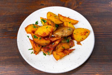 Dışı çıtır çıtır, içi yumuşak, içi kızarmış patatesler beyaz bir tabakta oturur. Taze otlar yemeği güçlendirir, bu da onu çekici bir yan ya da atıştırmalık seçeneği yapar..