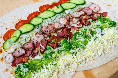 Canlı bir paket ızgara tavuk, çeşitli etler, taze marul, salatalık, salatalık ve rengarenk malzemeler sergilenen dilimlenmiş peynir ile hazırlanır..