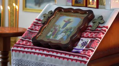 Mum ışığıyla dolu huzurlu bir atmosfer, dini bir ikonun yer aldığı güzel süslenmiş bir sunağı çevrelemektedir. Toplantının bir saygı ve maneviyatla ilgisi var..