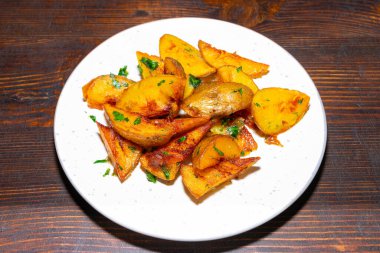 Taze otlarla süslenmiş lezzetli altın kavrulmuş patatesler beyaz bir tabakta servis edilir. Bu yemek her yemek için mükemmel, çekici bir doku ve canlı renkler sergiliyor..