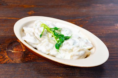 Lezzetli hamur köfteleri, üzerine taze otlar serpiştirilmiş kırsal bir kasede kaplanır. Lokantayı, enfes bir restoranda doyurucu bir yemek yemeye davet ederler..