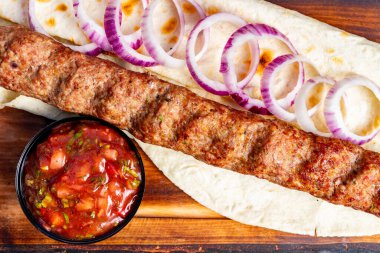 Ağız sulandıran bir kebap dürümü, dilimlenmiş kırmızı soğan eşliğinde mükemmel bir şekilde şişlenmiş ve lezzetli bir salsa sosuyla servis edilen sulu eti içerir. Günün her saatinde lezzetli bir yemek için ideal..