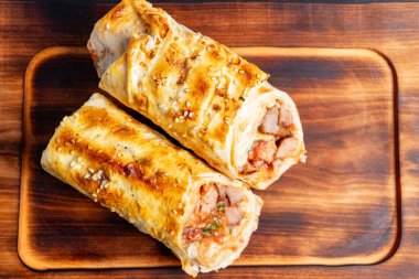 İki altın sarısı kahverengi salata mükemmel pişmiş, lezzetli karides ve taze sebzelerle dolu, kırsal bir ahşap kesme tahtasının üzerinde sergileniyor..