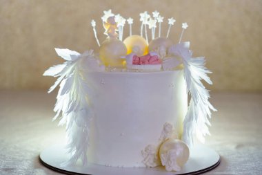 Karmaşık dekorasyonlarla özenle hazırlanmış çarpıcı beyaz bir pasta. Zarif tüyler ve süs figürleri neşeli bir olay için sihirli bir süs oluşturur, hafifçe aydınlatılır..