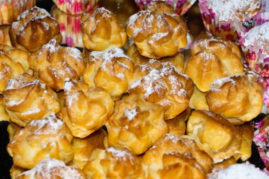Bir tepside çeşitli lezzetli hamur işleri sunulur, toz şekere bulanır, bir kafe ortamında sıcak bir akşam toplantısında dikkatleri üzerine çeker..