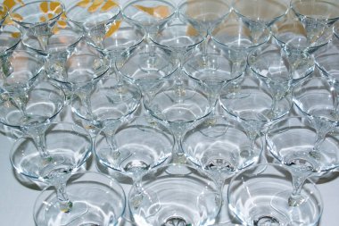 Işığı yansıtan ve çağdaş bir mekandaki bir kutlama etkinliğinde neşeli bir atmosfer yaratan güzel bir cam eşyalar dizisi piramit biçiminde sergilenir..