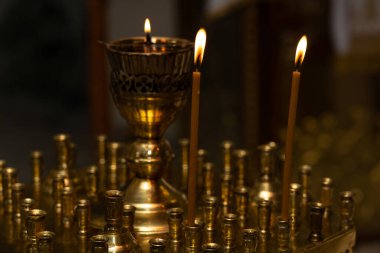 İki mumdan çıkan parlak alevler ve dekoratif bir gaz lambası huzurlu bir ibadethanede sıcak bir ortam yaratır. Altın rengi, akşam ayinine huzur katıyor.