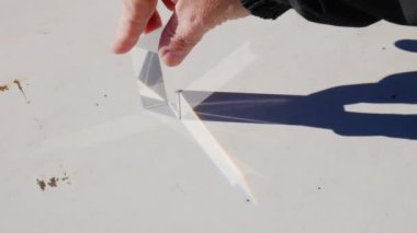 Hand moving a triangular prism in full sunlight and creating the refraction and decomposition of sunlight in the colors of the rainbow on a rusty white metal plate