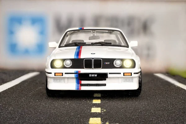 Madrid, İspanya; 12-10-2023: 1986 yılından kalma beyaz bir Bmw M3 E30 spor otomobilinin ön görünümü, gemi konteynırlarının önünde bir yolda olduğunu canlandırmak