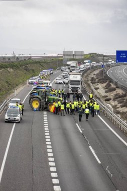 Illescas, Toledo, İspanya; 02-07-2024: Toledo ilindeki A-42 otoyolunu kesen traktörler, İspanyol çiftçilerin tehlikeli durumları nedeniyle trafik gecikmelerine yol açtılar