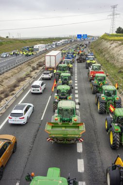 Illescas, Toledo, İspanya; 02-07-2024: Toledo ilindeki A-42 otoyolunu kesen traktörler, İspanyol çiftçilerin tehlikeli durumları nedeniyle trafik gecikmelerine yol açtılar