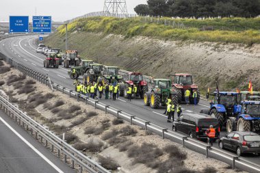Illescas, Toledo, İspanya; 02-07-2024: Toledo ilindeki A-42 otoyolunu kesen traktörler, İspanyol çiftçilerin tehlikeli durumları nedeniyle trafik gecikmelerine yol açtılar