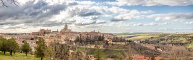 Segovia 'nın panoramik manzarasından Katedral' i ve şehrin ünlü su kemerini görebiliriz. Kış günbatımında bulutlu bir gökyüzü ile.