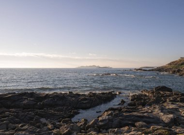 Bir yaz günü gün batımında Bainoa gezinti güvertesinden Atlantik Okyanusu ve Cies Adaları takımadalarının manzarası dalgalar kıyıya yakın sulardan çıkan kayalara vururken