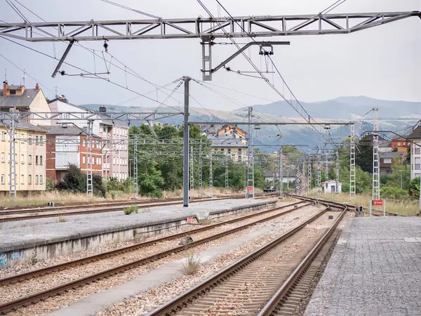 stock image View of the end of the platform at Ponferrada train station on its way out towards the mountains where the low signals are illuminated in red under the wires of the catenary