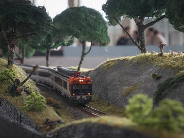 Ponferrada, Leon, İspanya; 10-20-2024: Renfe lokomotiflerinin taşlarla, ağaçlarla ve koyunlarla çevrili bir viraj aldığı demiryolu modelleri sergisi