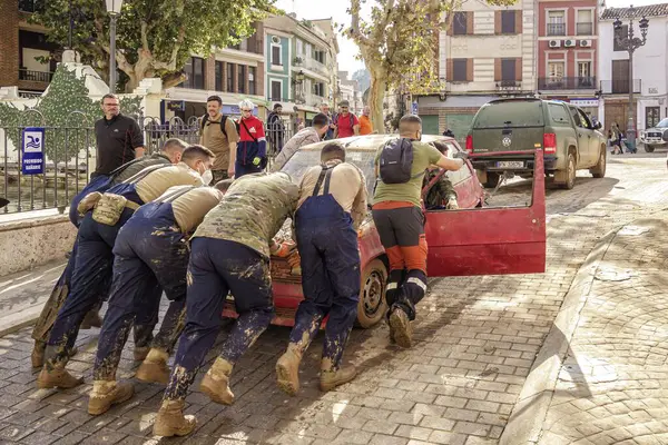 Chiva, Valencia, İspanya; 11-06-2024: İspanya Askeri Acil Durum Birimi (UME) askerleri, Valensiya Topluluğu 'nda Dana' nın sağanak yağmurundan zarar gören bir aracı ittiler