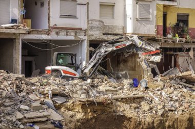 Chiva, Valencia, İspanya; 11-06-2024: Valensiya Topluluğu üzerinde Dana 'nın şiddetli yağmurlarının yol açtığı selden zarar gören binaların kontrollü bir şekilde yıkılması sonrasında kazıcı molozları temizliyor