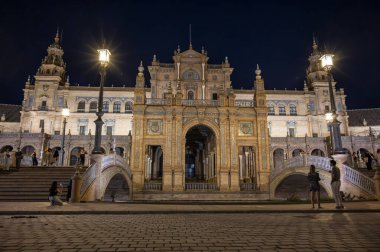 Sevilla, İspanya; 09 / 27 / 2024: Sevilla, İspanya 'daki Plaza de Espaa' nın büyük girişi, gece güzelce aydınlatıldı. Karmaşık kemerler ve süslü detaylar şehrin mimari ihtişamını vurguluyor