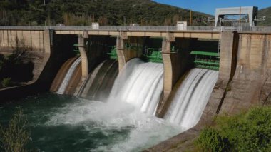 İki baraj kapağının açık olduğu Sil Nehri 'ndeki Pearrubia rezervuar barajının genel manzarası büyük bir su akışını serbest bırakarak aşağı doğru beyaz bir dere oluşturuyor.