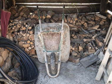Çiftlik kulübesi ısıtma için odun depolamak için kullanılan odun ocağı, paslı el arabaları ve çiftlik ve bahçe aletleri için kullanılan çeşitli aletler.