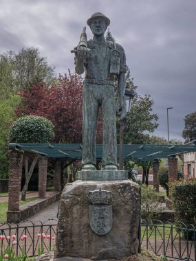 Torre del Bierzo, Leon, İspanya; 04-17-2025: Gömlek kollarıyla bir madenciyi onurlandıran bronz heykel, bir çekiç, bir karbit lamba ve şehrin arması üzerindeki bir parkta bulunan bir balta