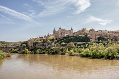 Alczar Kalesi, Tagus Nehri ve tarihi Alcantara Köprüsü ile Toledo 'nun panoramik manzarası mimari, doğa ve ortaçağ mirasının harmanlanması.