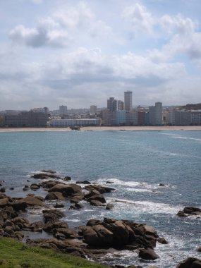 Galiçya 'nın A Coruna şehrindeki Orzan Koyu ve Riazor plajı manzarası. Yüksek binalar sahili ve kayalarını kaplayan Atlantik Okyanusu' na açılan körfezin manzarasının keyfini çıkarırlar.